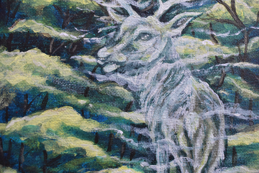 Close-up of a needlepoint or cross-stitch piece depicting a deer in a natural setting.